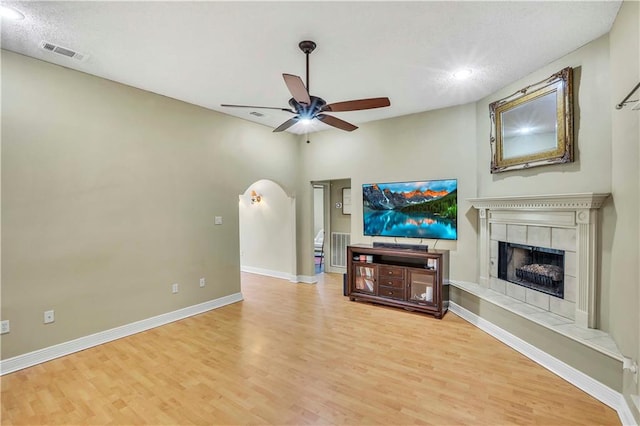 living room featuring light hardwood / wood-style floors, ceiling fan, and a tile fireplace