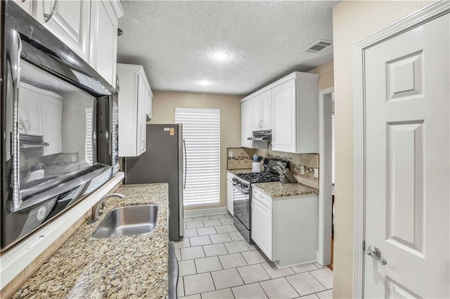 kitchen with range with gas stovetop, white cabinetry, sink, and light stone counters