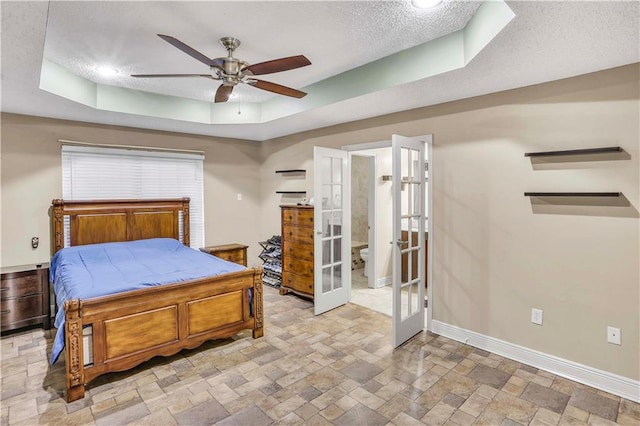 bedroom with french doors, ensuite bath, ceiling fan, and a raised ceiling