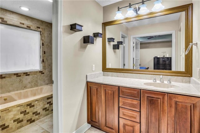 bathroom with a relaxing tiled tub, tile patterned flooring, and vanity