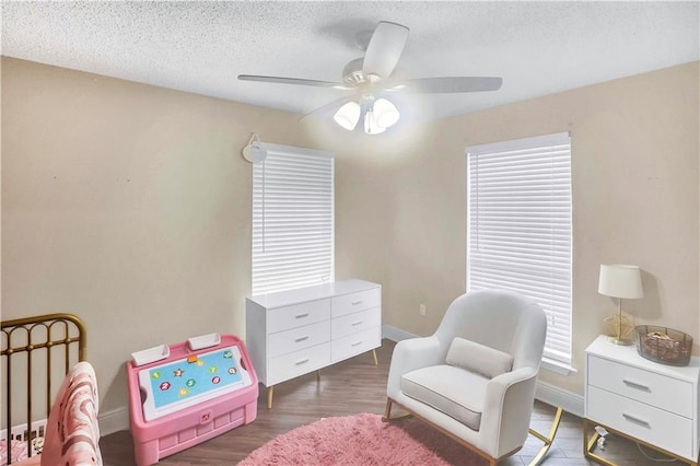 sitting room with a textured ceiling, dark wood-type flooring, and ceiling fan