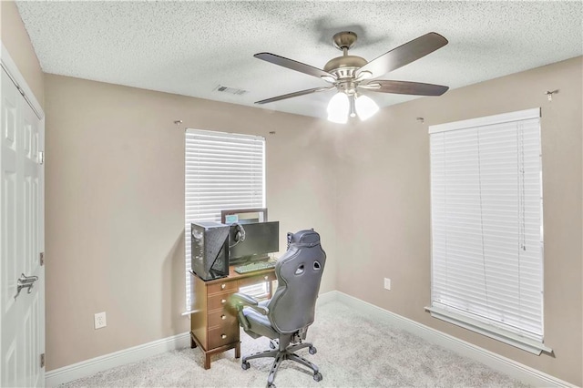 carpeted office with a textured ceiling and ceiling fan