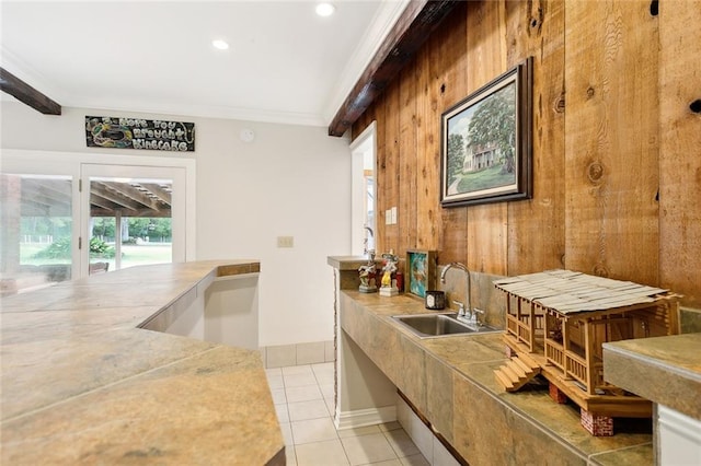 interior space featuring wood walls, sink, light tile patterned flooring, crown molding, and beam ceiling