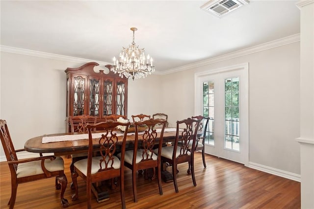 dining space featuring wood-type flooring, a chandelier, and crown molding