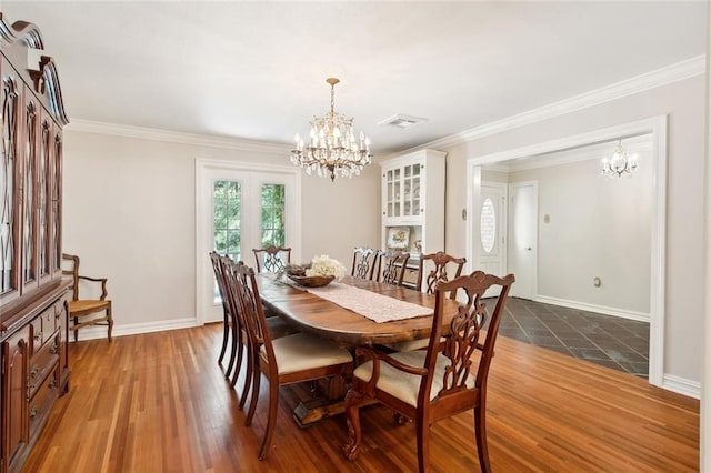 dining room featuring dark hardwood / wood-style floors, crown molding, and an inviting chandelier