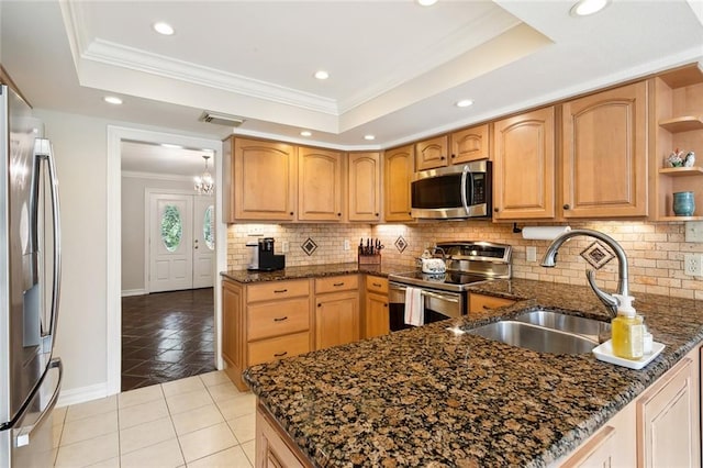 kitchen featuring stainless steel appliances, dark stone counters, a raised ceiling, and kitchen peninsula