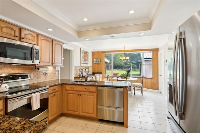 kitchen with stainless steel appliances, sink, kitchen peninsula, dark stone countertops, and hanging light fixtures