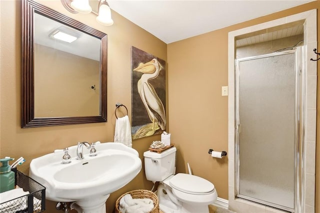 bathroom with toilet, sink, and a shower with shower door