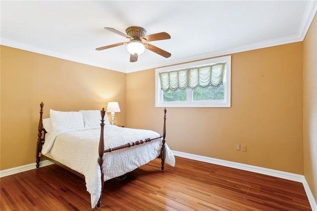 bedroom with a ceiling fan, crown molding, baseboards, and wood finished floors
