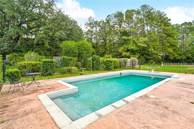 outdoor pool featuring a yard, fence, and a patio area