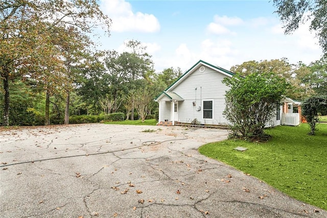 view of property exterior featuring driveway, entry steps, and a yard