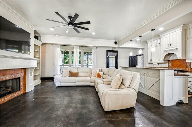 living room featuring a tiled fireplace, ceiling fan, built in features, and crown molding