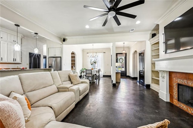 living room with a tiled fireplace, ceiling fan, built in features, and ornamental molding