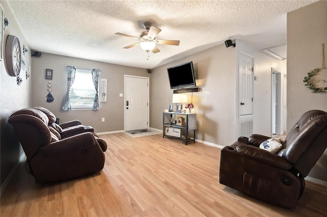 living room featuring ceiling fan, a textured ceiling, and light hardwood / wood-style flooring