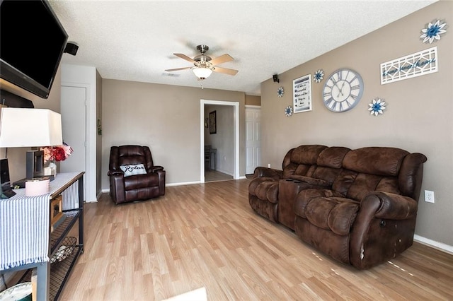 living room with a textured ceiling, light hardwood / wood-style floors, and ceiling fan