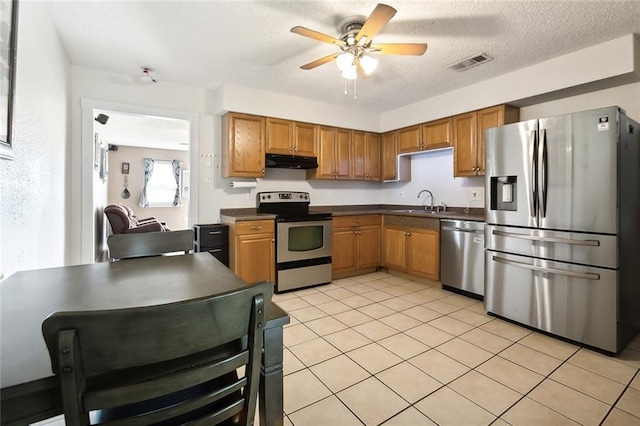 kitchen featuring a textured ceiling, stainless steel appliances, ceiling fan, and light tile patterned flooring