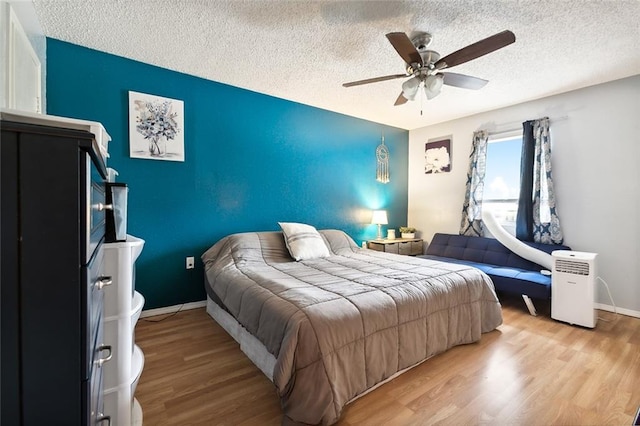 bedroom with light wood-type flooring, a textured ceiling, and ceiling fan