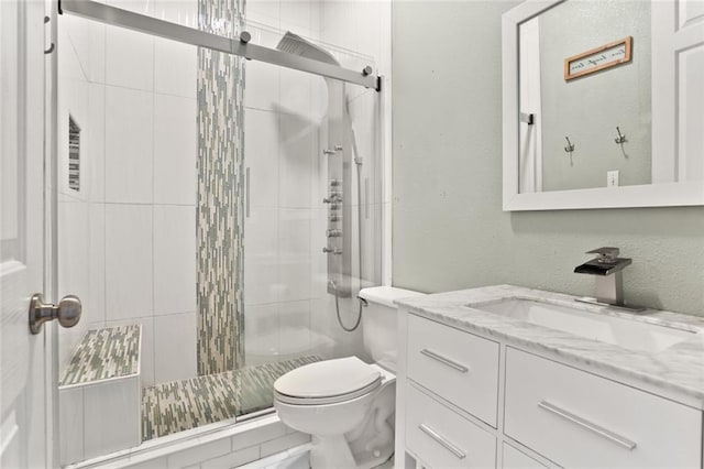 bathroom featuring toilet, vanity, and a shower with shower door