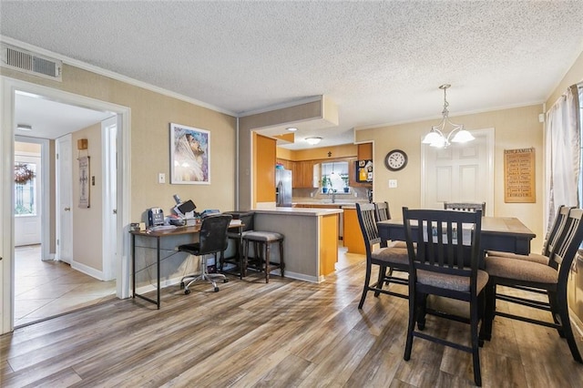 dining area with wood-type flooring, a notable chandelier, crown molding, and a textured ceiling