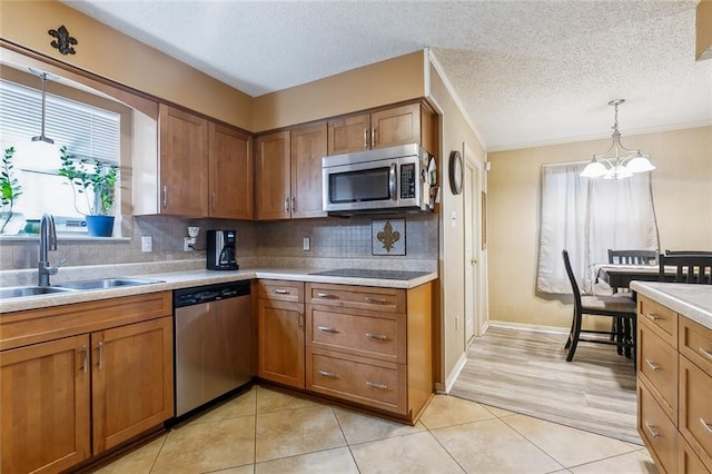 kitchen with stainless steel appliances, sink, a textured ceiling, an inviting chandelier, and backsplash