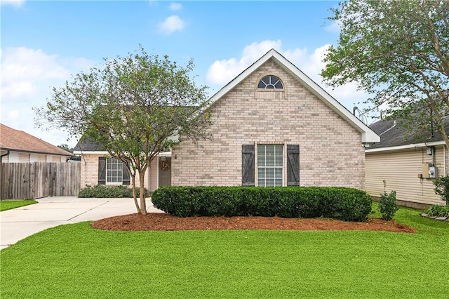 view of front of house featuring driveway, brick siding, a front lawn, and fence