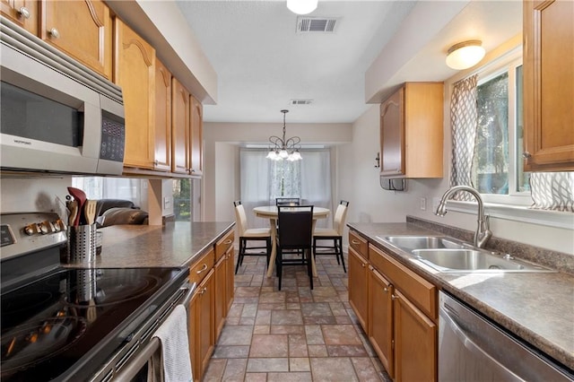 kitchen featuring stainless steel appliances, hanging light fixtures, sink, and a notable chandelier