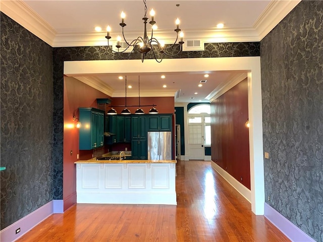 kitchen with light hardwood / wood-style floors, stainless steel fridge, kitchen peninsula, and crown molding