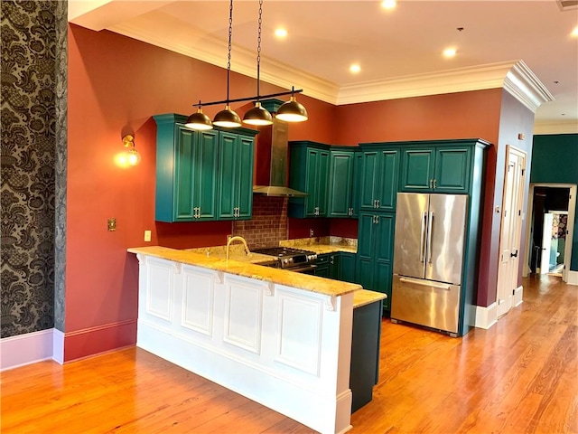 kitchen with kitchen peninsula, stainless steel appliances, light hardwood / wood-style floors, and wall chimney range hood