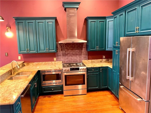 kitchen with light wood-type flooring, decorative columns, high end appliances, sink, and wall chimney range hood