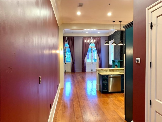 kitchen with hanging light fixtures, light hardwood / wood-style flooring, stainless steel dishwasher, and ornamental molding