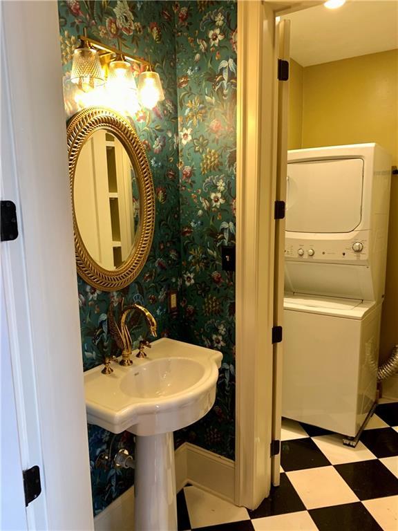 1225 Bourbon St Unit B, New Orleans, LA 70116 - bathroom featuring tile patterned floors, stacked washing machine and dryer, and wallpapered walls