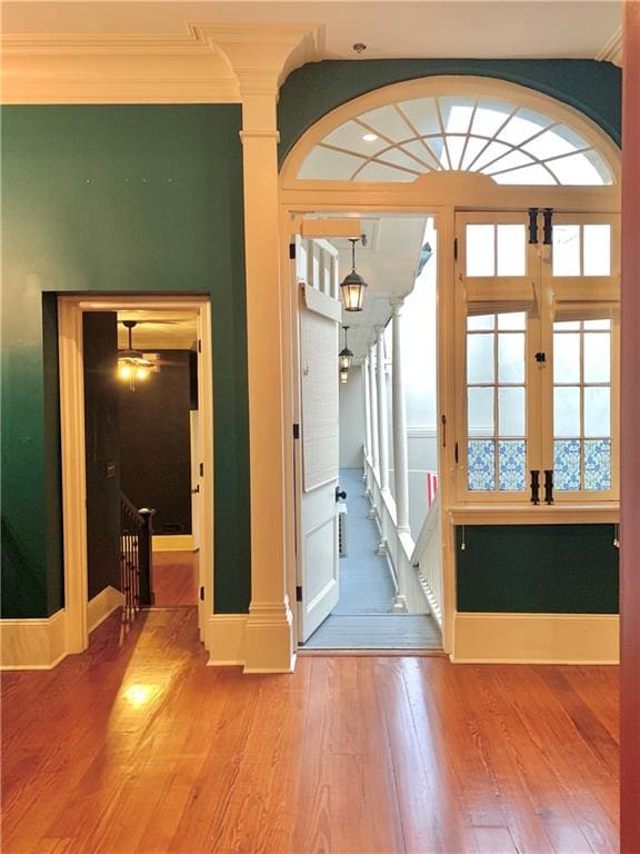 doorway to outside with wood-type flooring and crown molding