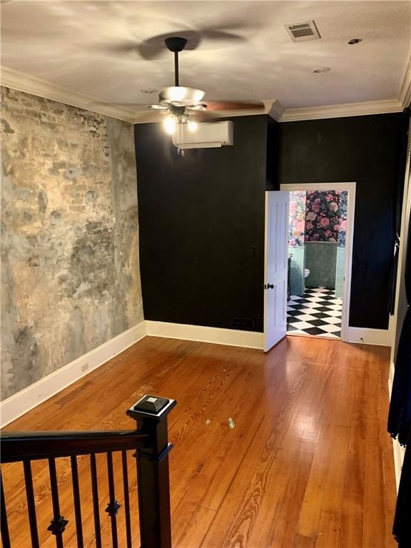 empty room featuring wood-type flooring, a wall unit AC, ceiling fan, and ornamental molding