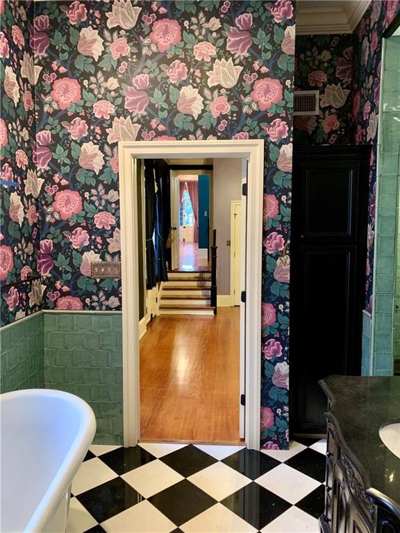 bathroom with hardwood / wood-style floors, vanity, a tub to relax in, and crown molding