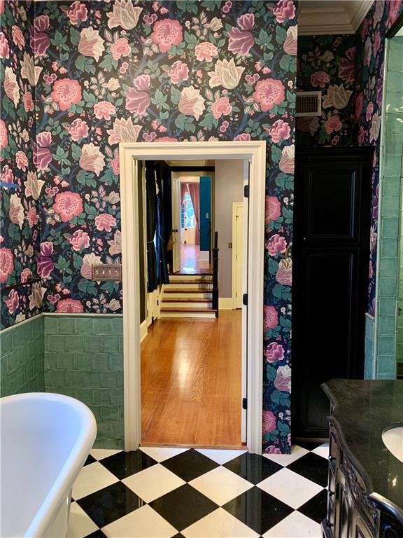 1225 Bourbon St Unit B, New Orleans, LA 70116 - bathroom featuring tile patterned floors, wallpapered walls, a soaking tub, vanity, and crown molding