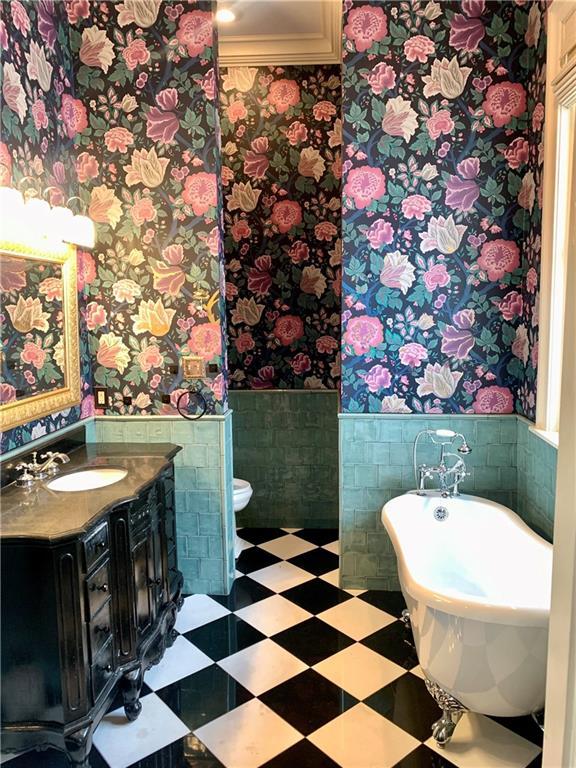 1225 Bourbon St Unit B, New Orleans, LA 70116 - full bathroom featuring wallpapered walls, a wainscoted wall, vanity, a soaking tub, and tile walls