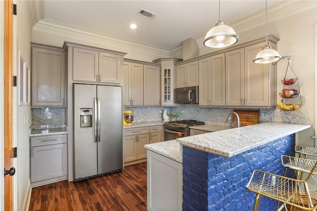 kitchen with light stone countertops, kitchen peninsula, dark hardwood / wood-style flooring, stainless steel appliances, and decorative light fixtures