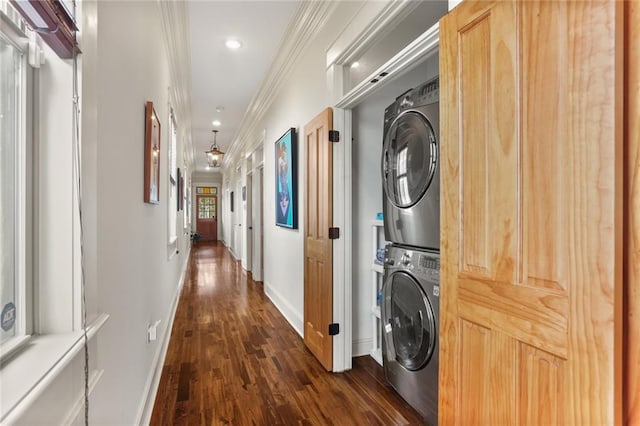 washroom featuring dark wood-type flooring, crown molding, and stacked washer and clothes dryer