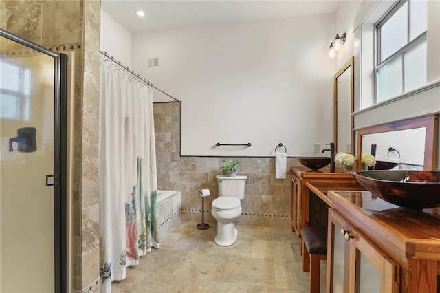 bathroom featuring toilet, vanity, tile walls, and walk in shower