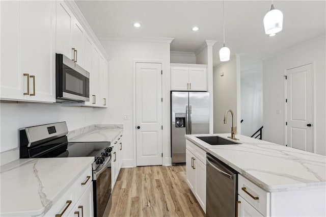 kitchen featuring sink, appliances with stainless steel finishes, light wood-type flooring, white cabinets, and pendant lighting