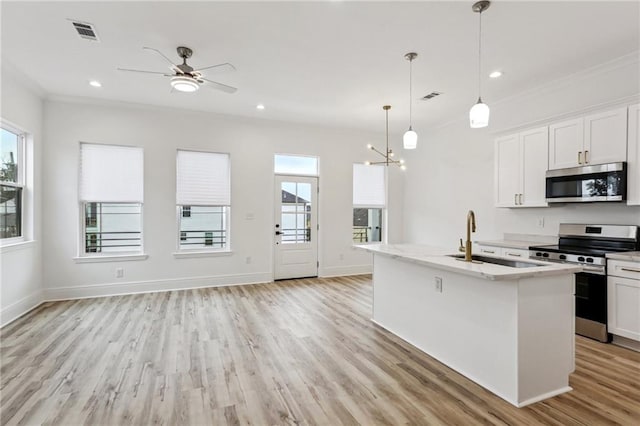 kitchen with stainless steel appliances, a wealth of natural light, white cabinetry, and a center island with sink