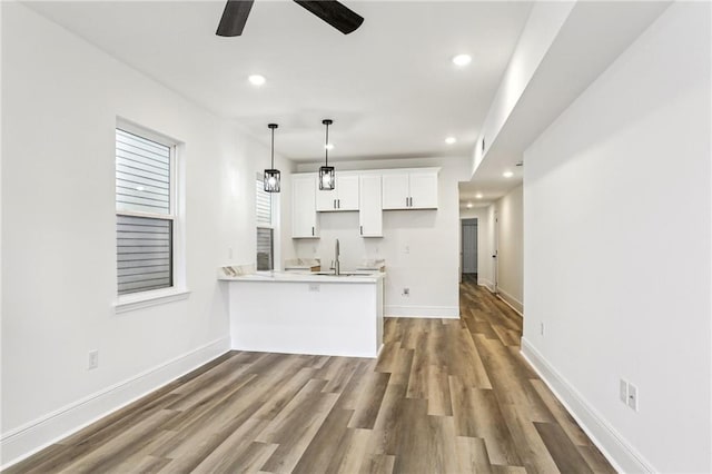 kitchen featuring kitchen peninsula, ceiling fan, hardwood / wood-style floors, white cabinets, and pendant lighting