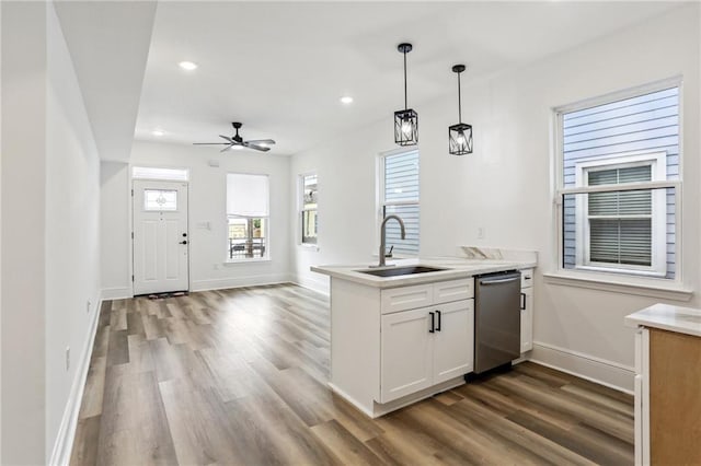 kitchen featuring white cabinets, kitchen peninsula, hardwood / wood-style floors, stainless steel dishwasher, and decorative light fixtures