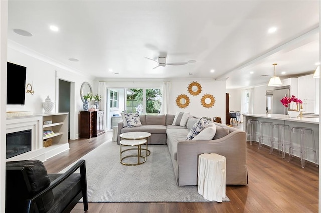 living room with ornamental molding, light wood-type flooring, and ceiling fan