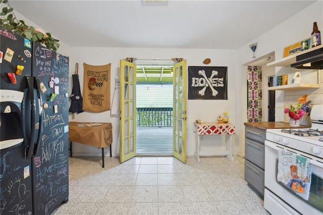 kitchen featuring black fridge with ice dispenser, white range with gas stovetop, and butcher block counters