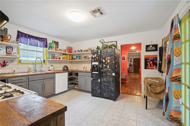 kitchen featuring black fridge, dishwasher, sink, tasteful backsplash, and gray cabinetry