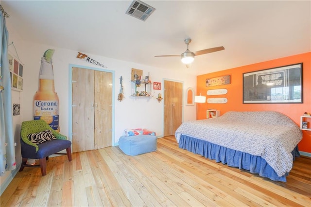 bedroom with ceiling fan, wood-type flooring, and multiple closets