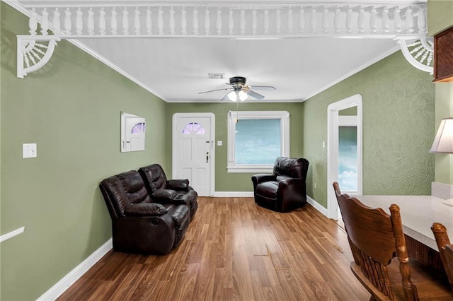 living room featuring ceiling fan, wood-type flooring, and crown molding