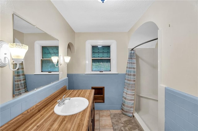 bathroom featuring tile walls, tile patterned floors, vanity, a textured ceiling, and a shower with shower curtain