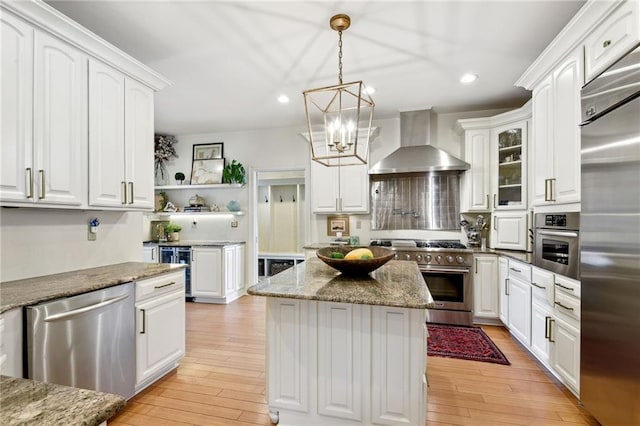 kitchen featuring white cabinets, wall chimney exhaust hood, high end appliances, and light hardwood / wood-style flooring